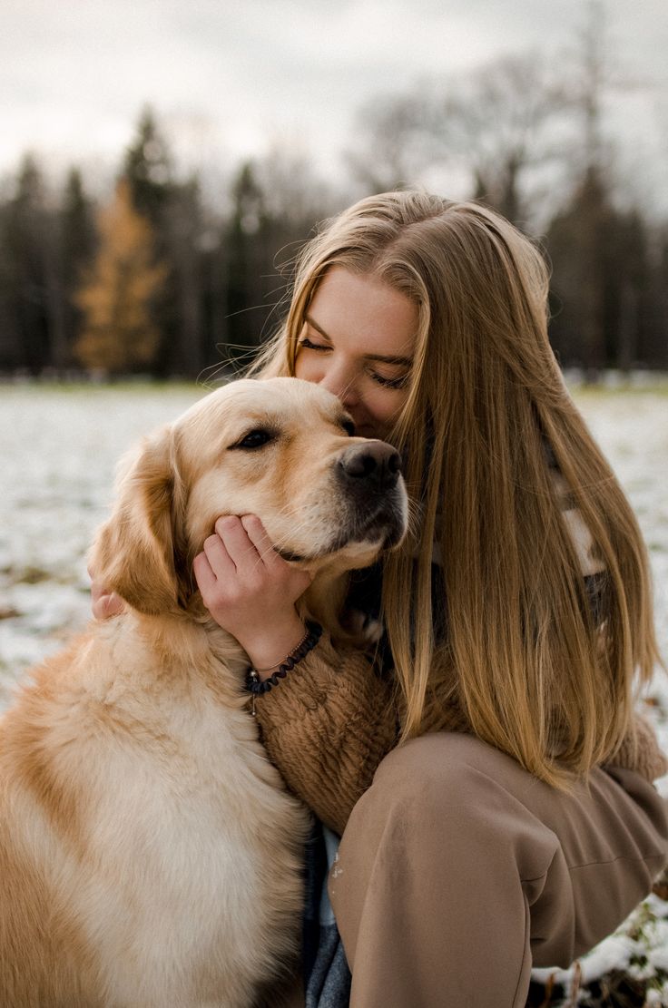 a woman is hugging her dog in the snow