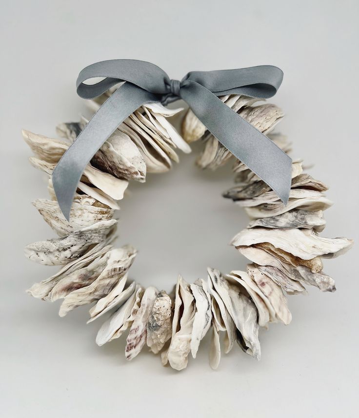 a wreath made out of seashells with a blue ribbon