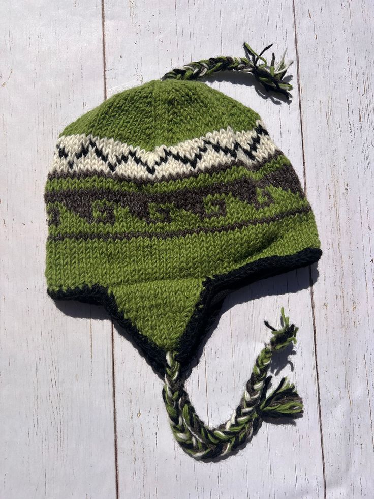 a knitted green and white hat laying on top of a wooden floor