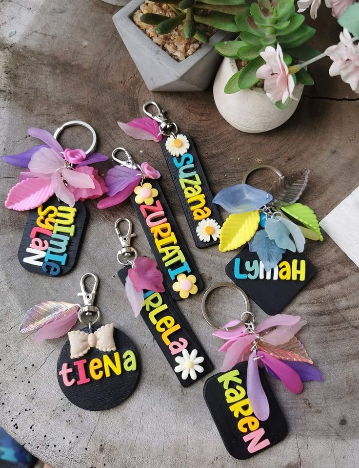 several key chains with flowers and name tags attached to them, sitting on a table