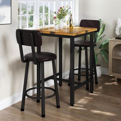 a kitchen table with two stools next to it and a vase filled with flowers