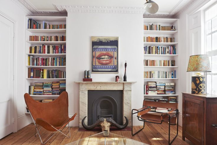 a living room filled with furniture and a fire place in front of a book shelf