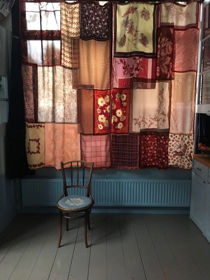 a chair sitting in front of a window covered with patchwork quilts and curtains