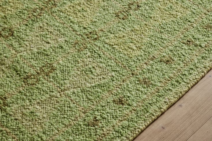 a green rug on top of a wooden floor