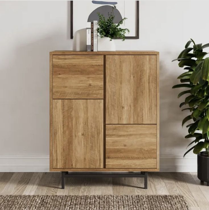 a wooden cabinet sitting on top of a hard wood floor next to a potted plant