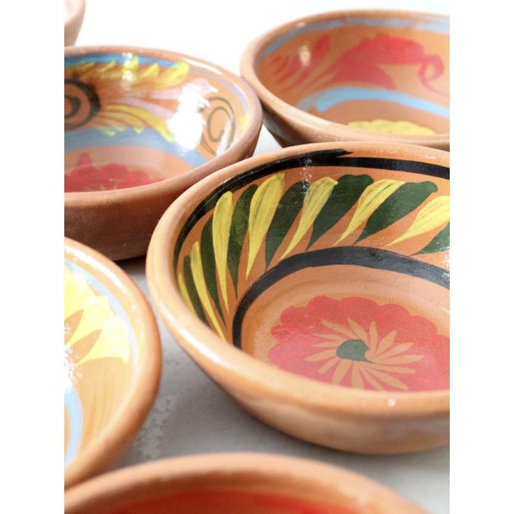 several bowls with designs painted on them sitting on a table