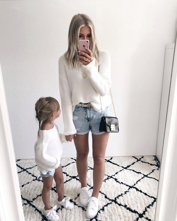 a woman taking a selfie with her toddler in front of a white wall