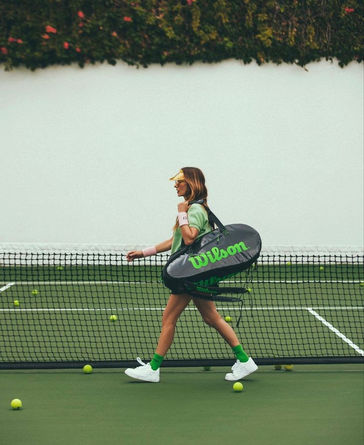 a woman holding a tennis racquet on top of a tennis court with balls in the air