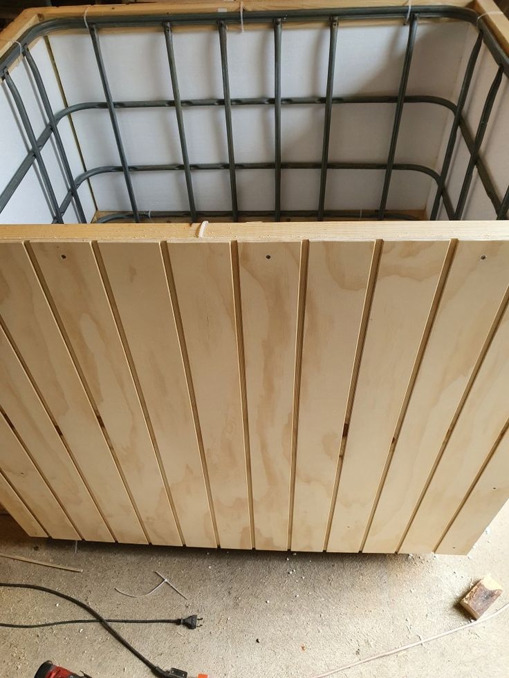 tools are laying on the floor in front of a wooden box with metal bars attached to it