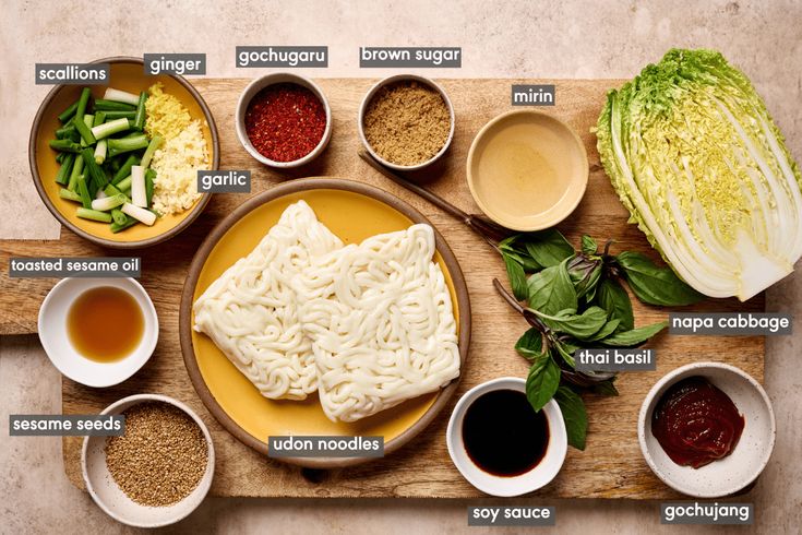 a wooden cutting board topped with bowls and plates filled with different types of food on top of it