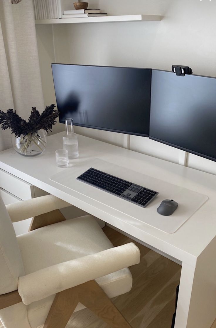 a white desk with two monitors and a keyboard