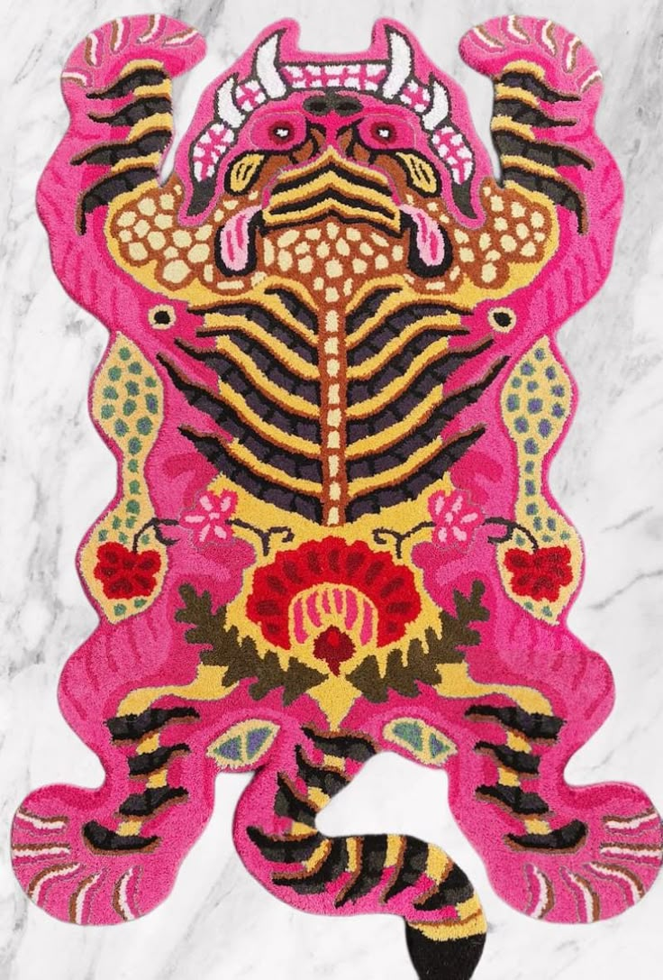 a pink and yellow rug with an animal design on it's back side, in front of a white marble background