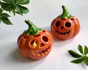 two pumpkin shaped candlesticks sitting next to each other