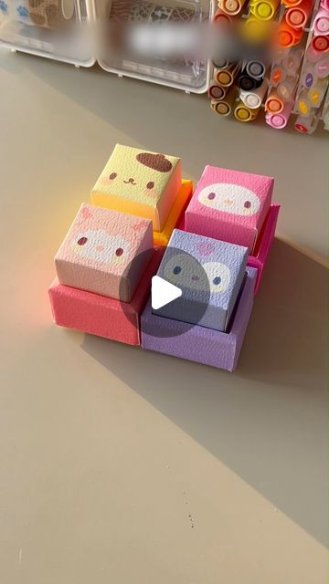 several colorful boxes with faces on them sitting on a table in front of some crafting supplies