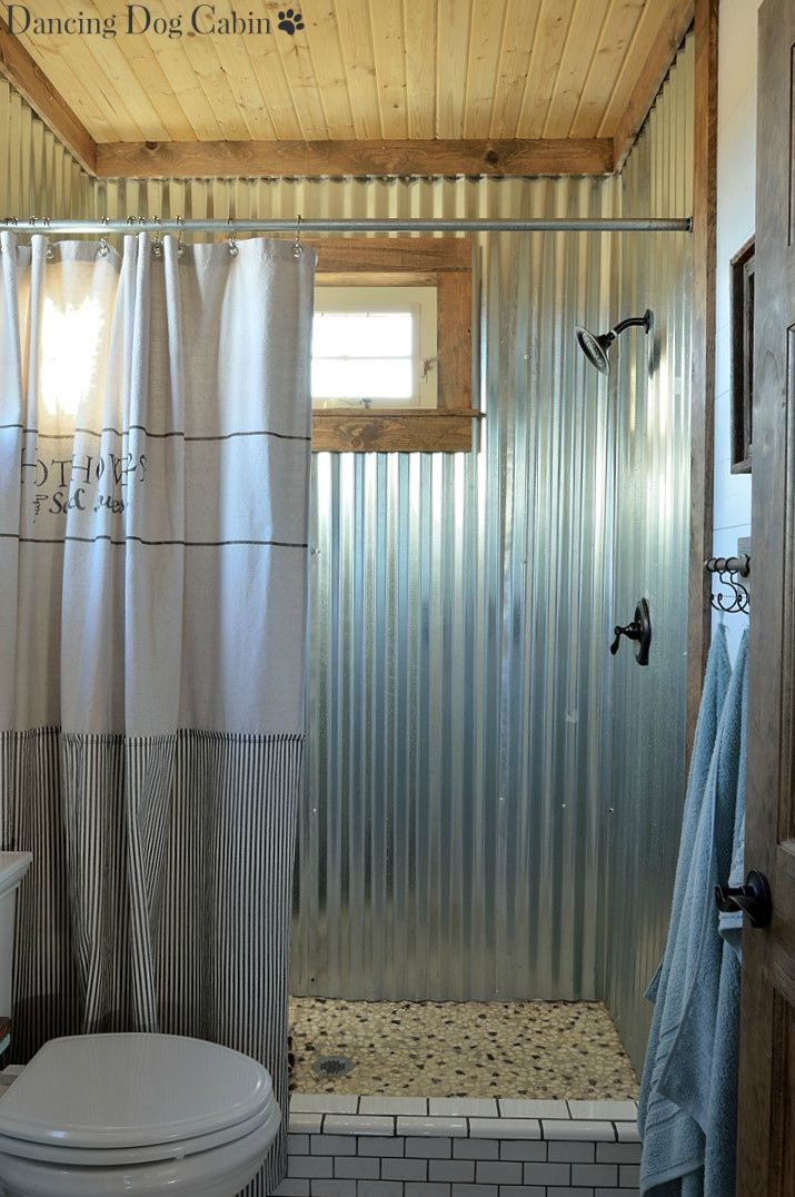 a white toilet sitting next to a shower in a bathroom under a wooden ceiling above a sink