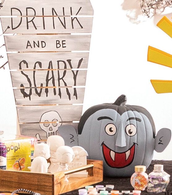 a table topped with lots of halloween decorations and decorating items in front of a sign that says drink, drink and be scary