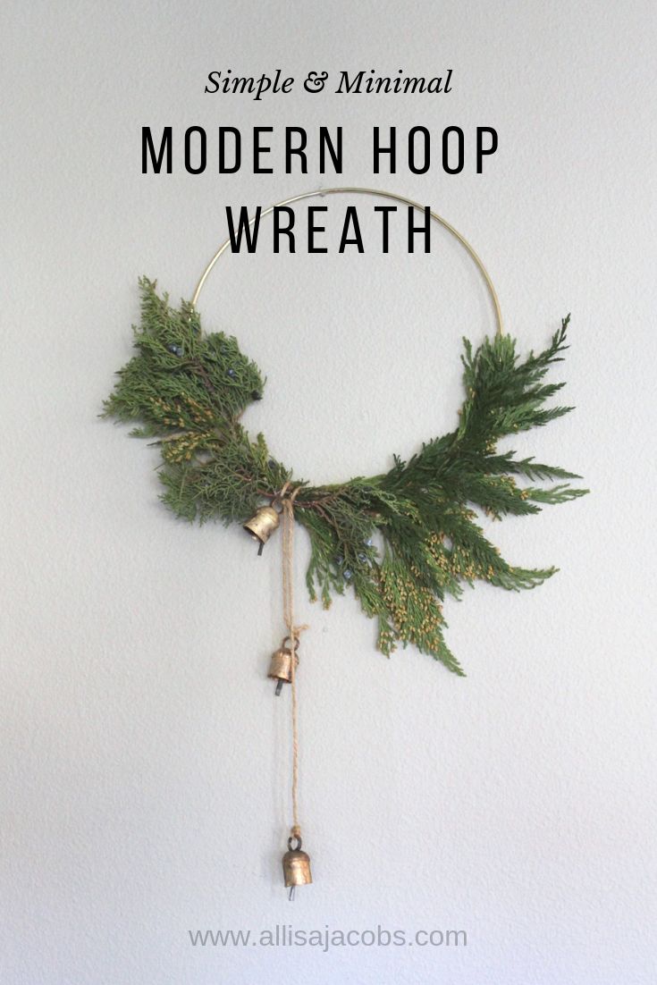 the simple and minimal modern hoop wreath is made with evergreen branches, bells and twine