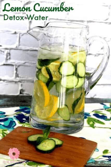 a pitcher filled with cucumber and lemon slices on top of a cutting board