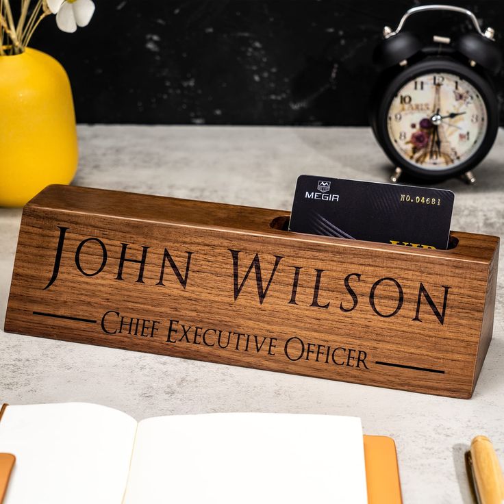 a wooden sign that says, john wilson chief executive officer with an alarm clock in the background