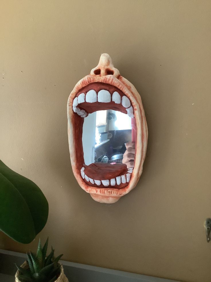 a mirror that is on the side of a wall with an open mouth in front of it