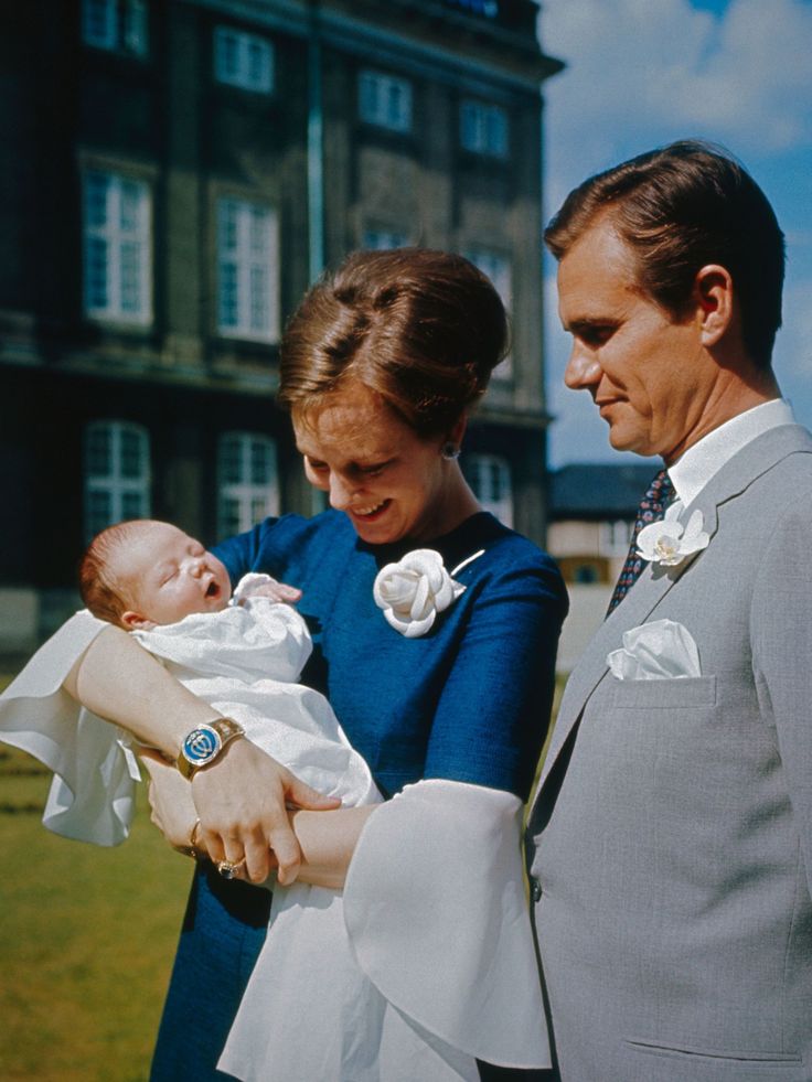 a man and woman holding a baby in front of a building