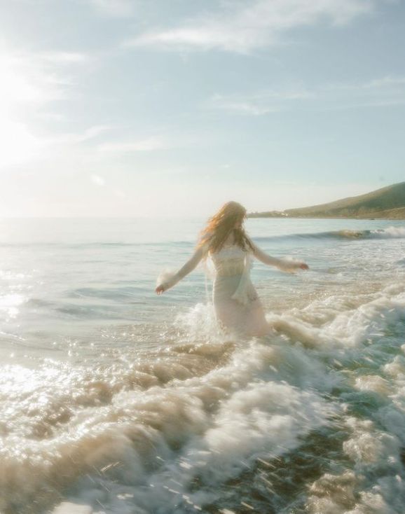 a woman is running in the water at the beach