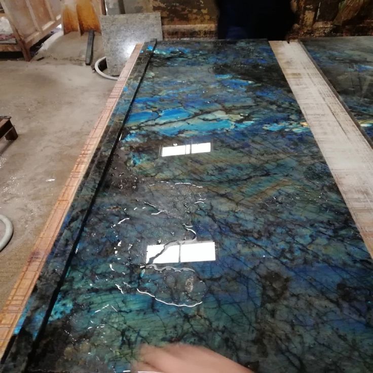 blue and green marble counter top being worked on in a factory area with workers working behind it