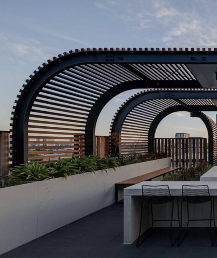 an outdoor dining area with tables and chairs under a pergolated roof at sunset