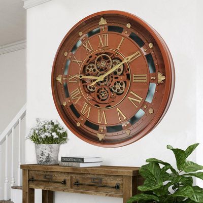 a large clock on the wall above a wooden table with potted plants in front of it