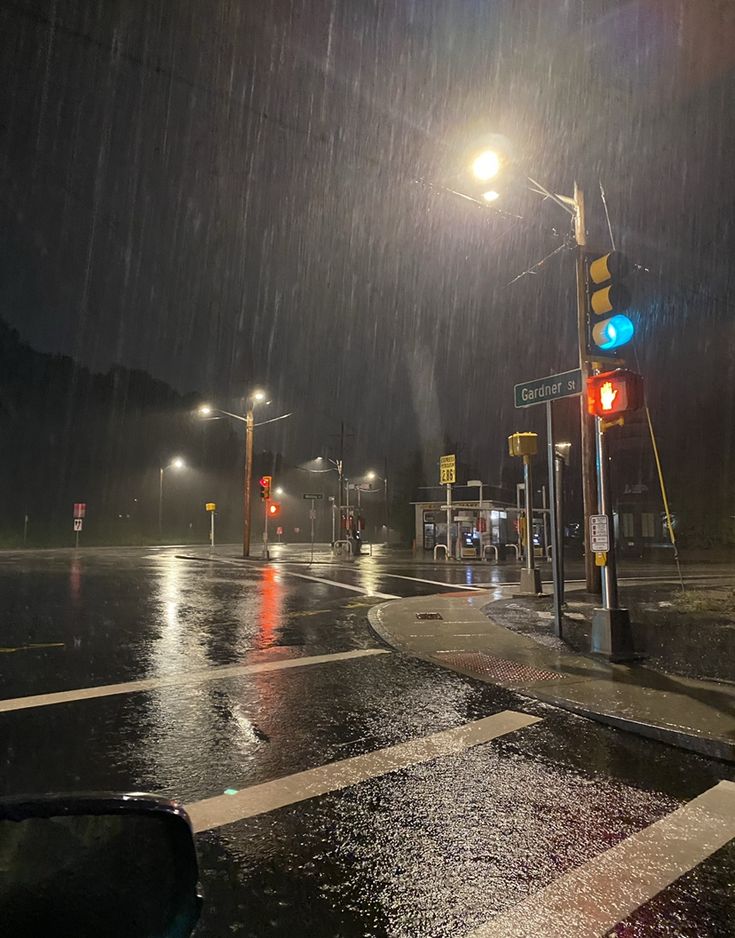 a rainy night at an intersection with traffic lights and street signs