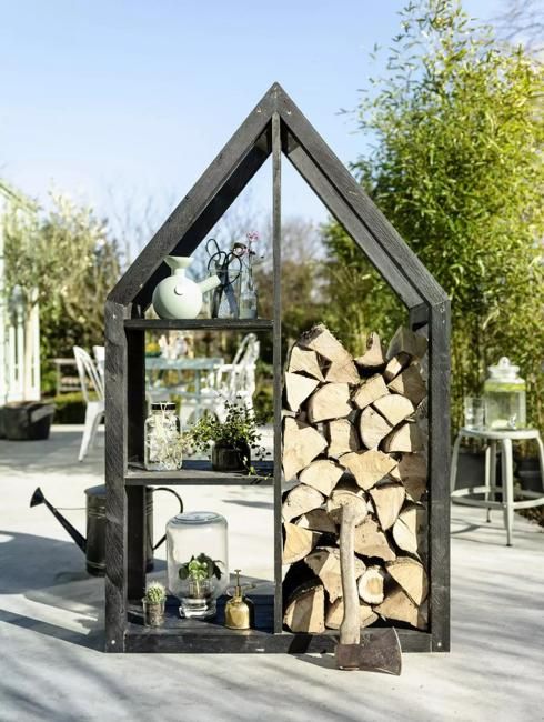 an outdoor fireplace made out of firewood in a house shaped like a log cabin