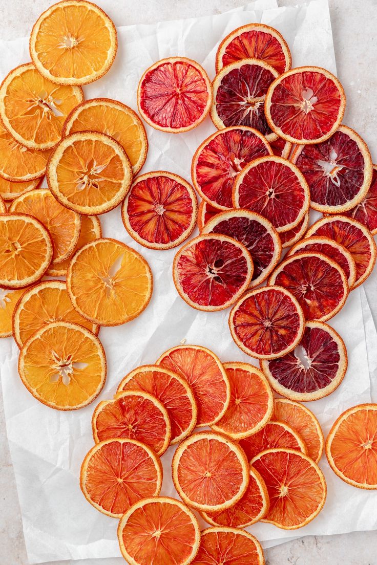 sliced oranges and blood orange slices on a piece of parchment paper with white wax