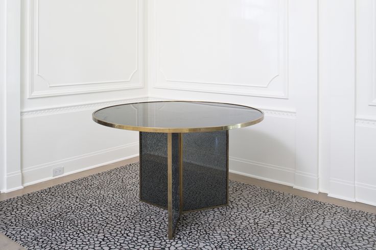 a round glass table sitting on top of a black and white rug next to a wall