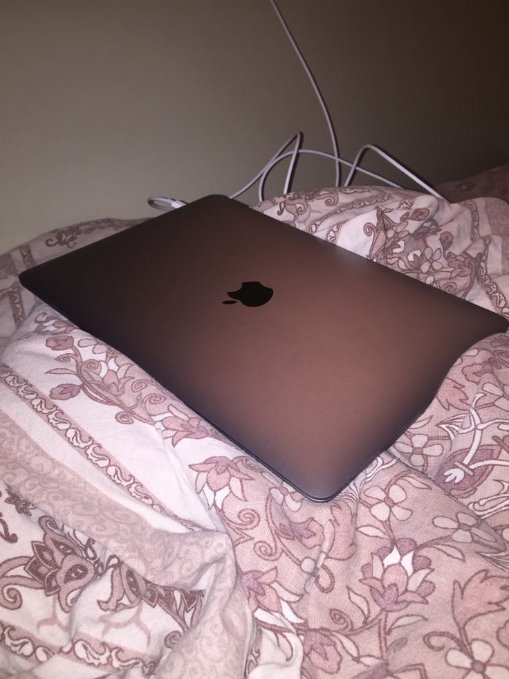 an apple laptop sitting on top of a bed