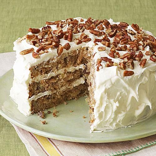 a carrot cake with white frosting and pecans on top