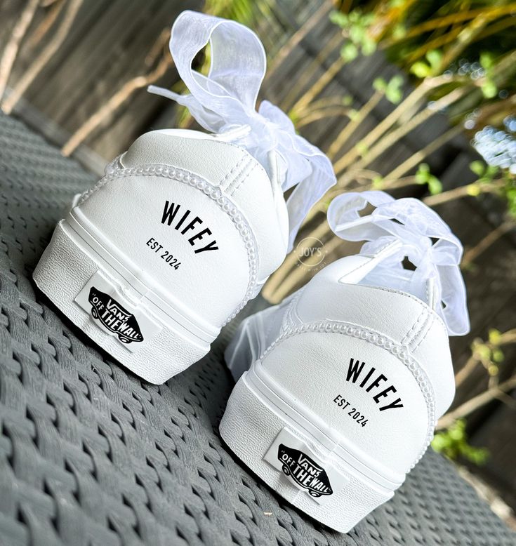 two white shoes with bows are sitting on a bench