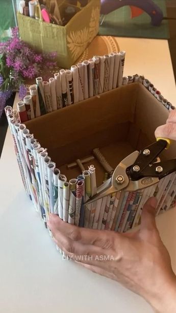 someone is holding scissors in a box made out of magazines