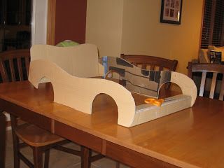 a cardboard boat sitting on top of a wooden table next to a dining room table