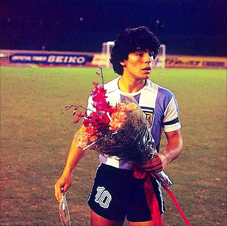 a young man holding a bouquet of flowers on top of a soccer field