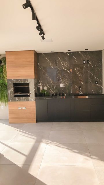 a modern kitchen with marble counter tops and black cabinets, along with potted plants on the wall