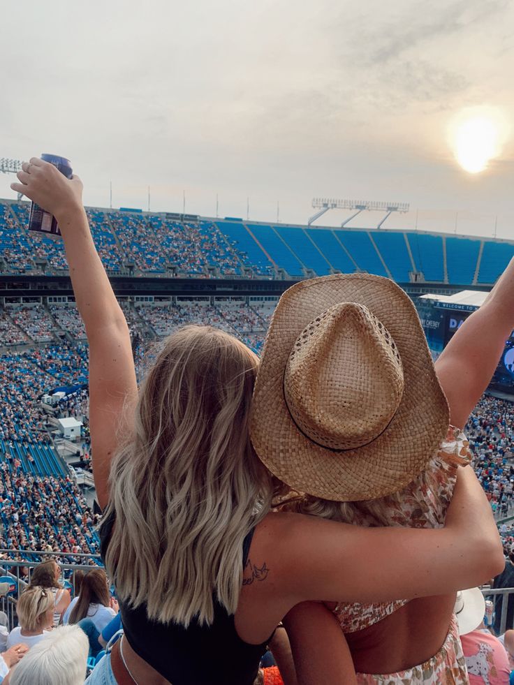 two women hugging each other in front of an audience at a sporting event with the sun setting