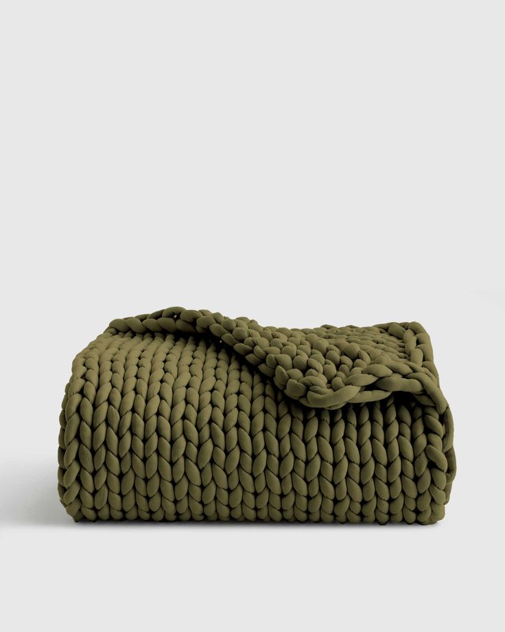 an olive green blanket folded on top of a white surface