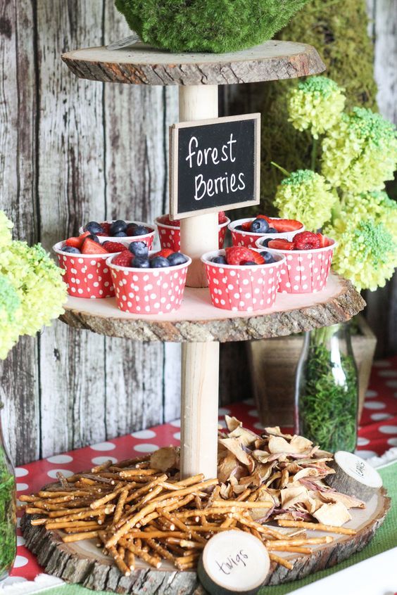 there is a sign that says forest bones on the top of a cake stand with cupcakes and strawberries