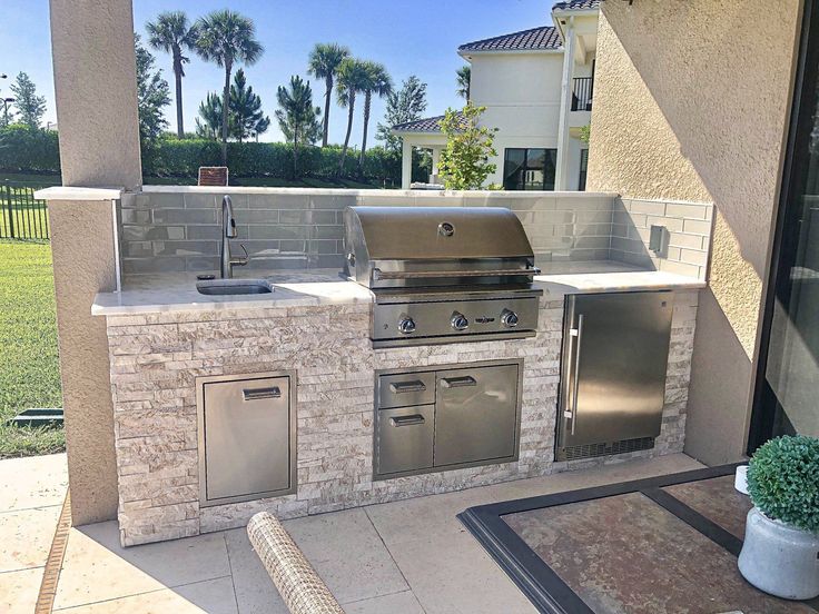 an outdoor kitchen with stainless steel appliances and grill