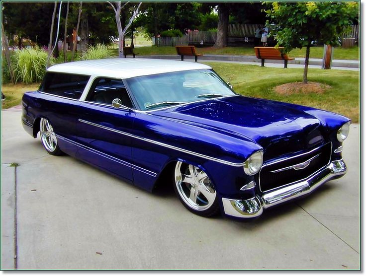 an old blue and white car parked on the street