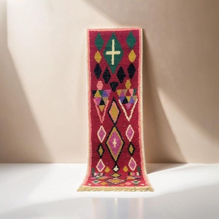 a colorful rug with a cross on the top is shown in front of a white wall