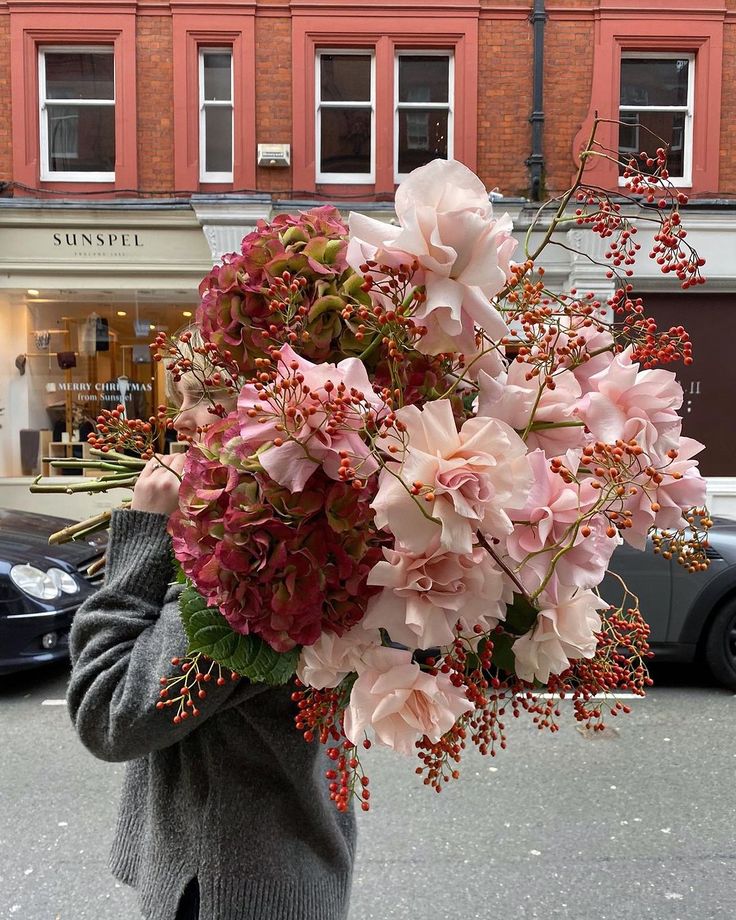 a person holding a bouquet of flowers in front of a building on a city street