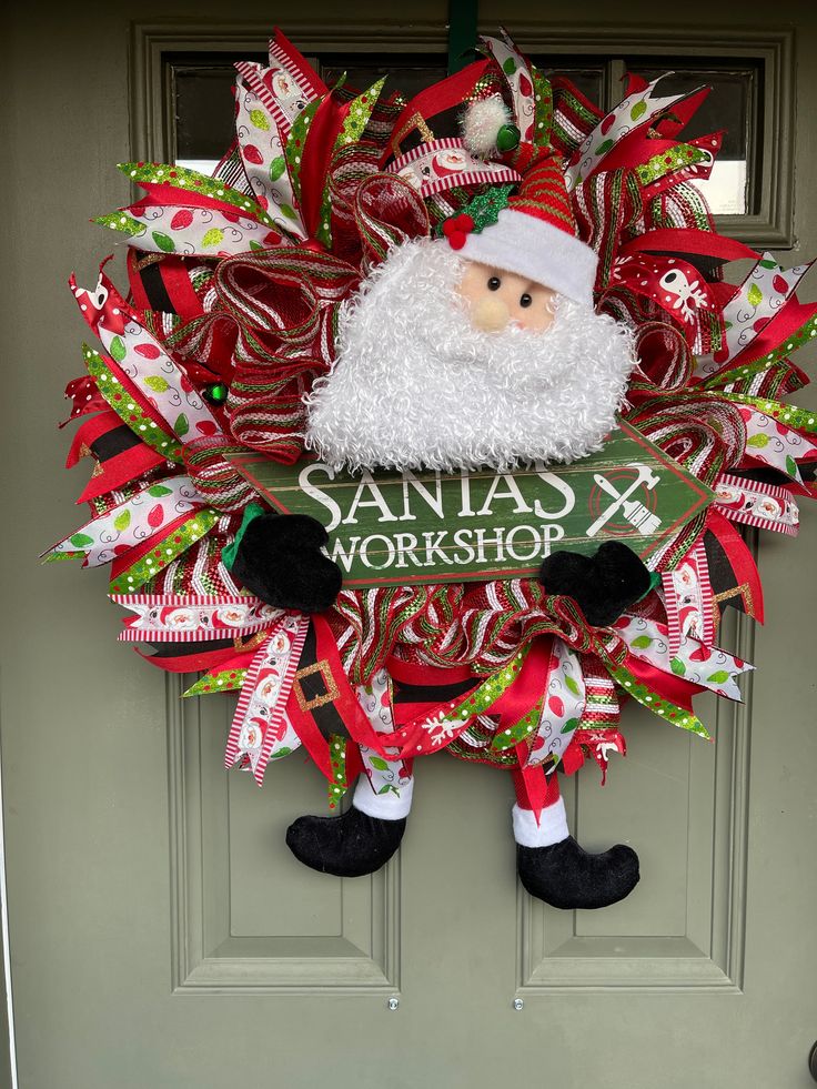 a christmas wreath with santa's workshop written on it, hanging from the front door