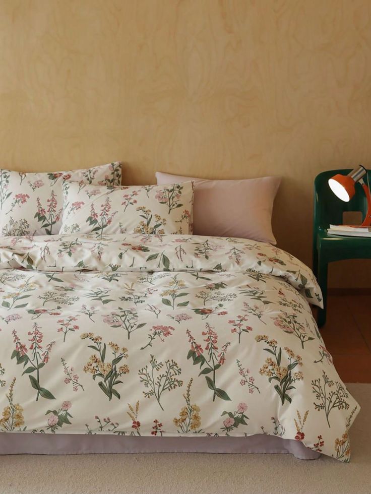 a bed with white and pink flowers on it in front of a green night stand