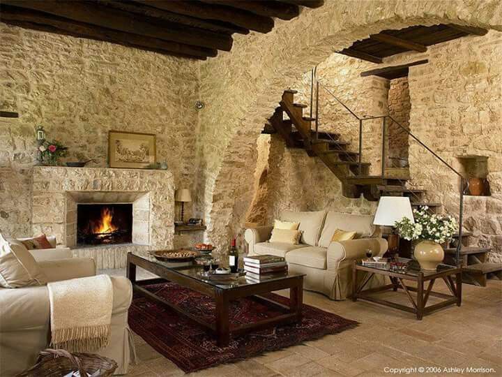 a living room filled with furniture and a fire place next to a stone wall fireplace